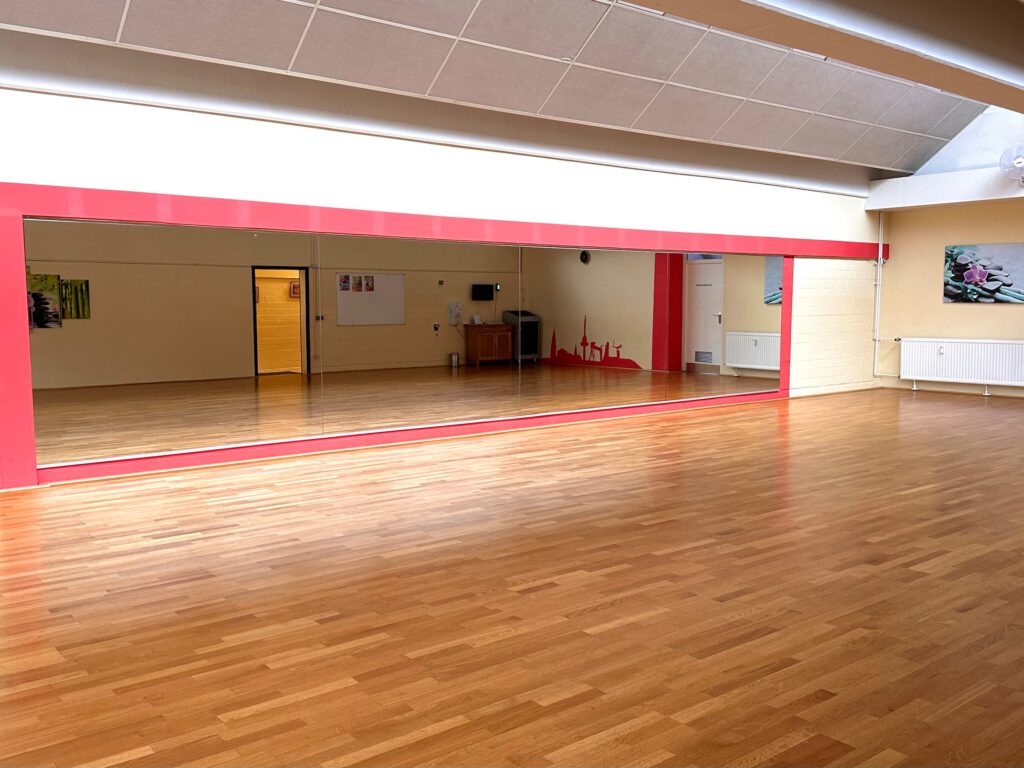 Tanzsaal mit Parkett und rot eingefasster Spiegelwand